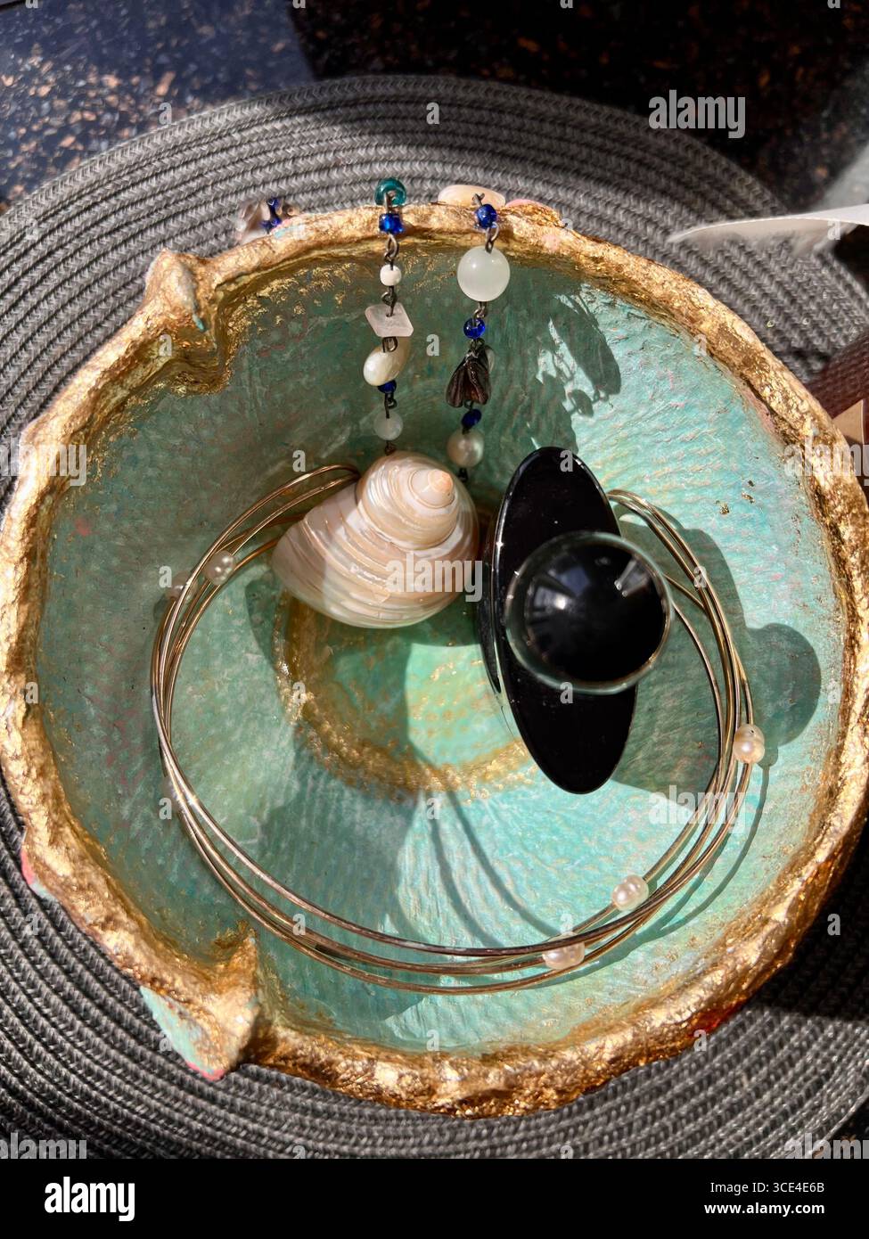 A decorative papier-mâché bowl in a soft blue shade, featuring a three-dimensional pink heart with gold trim - Smartphone Captured Stock Image