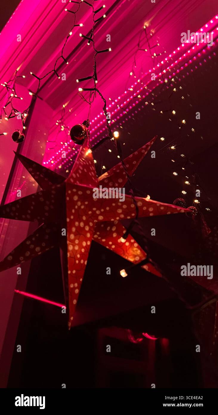 Night lights reflected in a stained glass window with red lighting under the ceiling, red papier Christmas star decor. - Smartphone Captured Stock Image