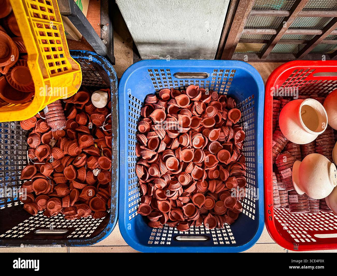 Aerial view of three baskets filled with small clay indian oil lamps or Diya and terracotta pots in an indian market setting, little india - Smartphone Captured Stock Image