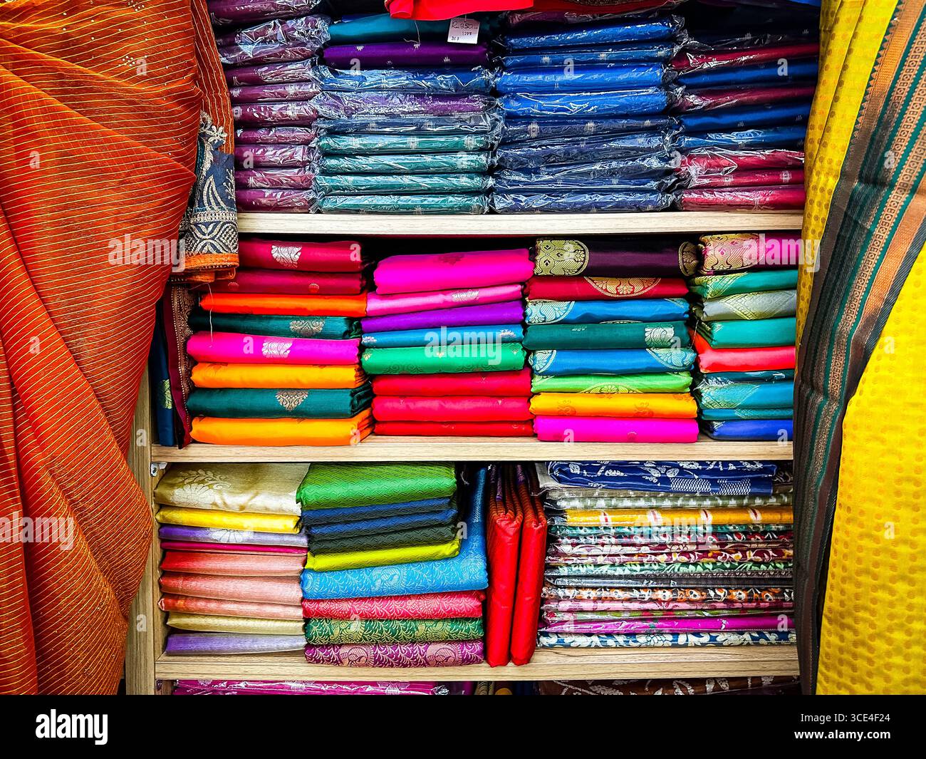 Stacks of vibrant and colorful fabric rolls on shelves in a textile shop, showcasing a variety of patterns and materials - Smartphone Captured Stock Image