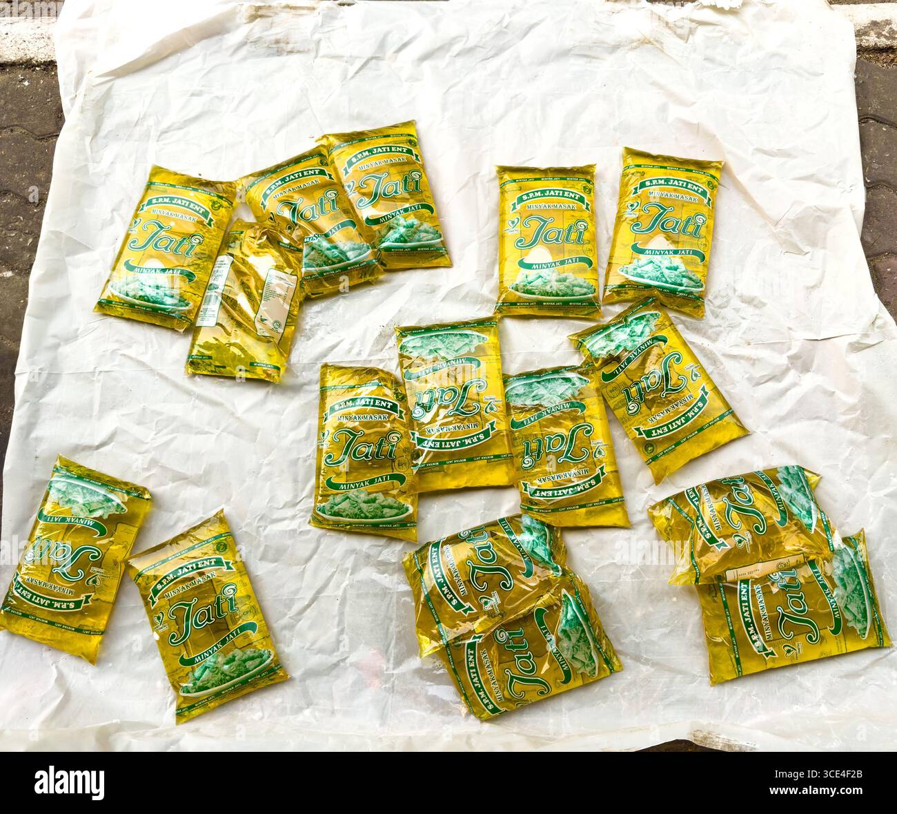 Assorted golden packets of Jati cooking oil from S.P.M. Jati  Ent. arranged on a white cloth surface showcasing a product variety malaysia - Smartphone Captured Stock Image