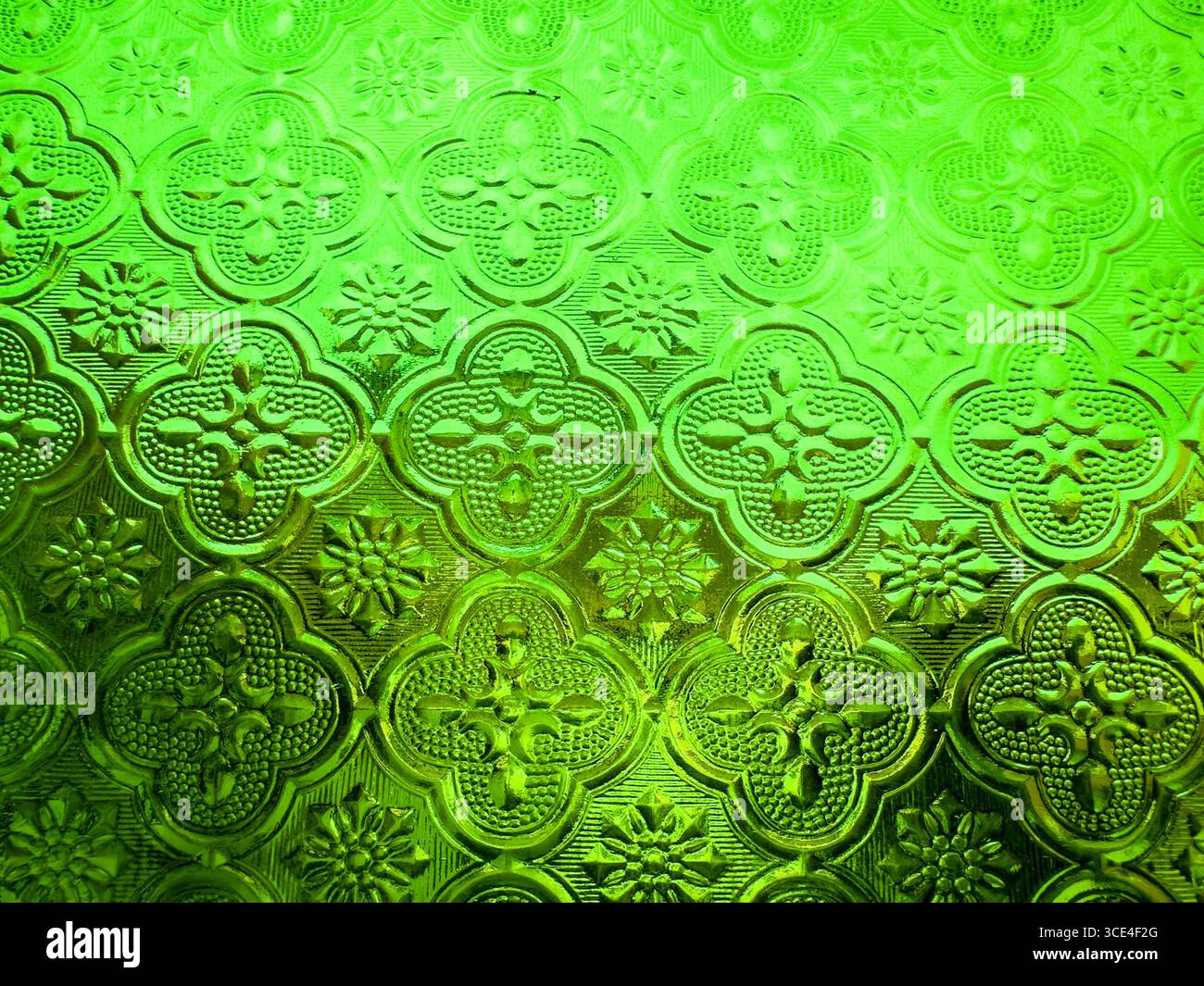 Close-up of textured green decorative glass with floral and geometric patterns creating a vintage stained glass effect - Smartphone Captured Stock Image