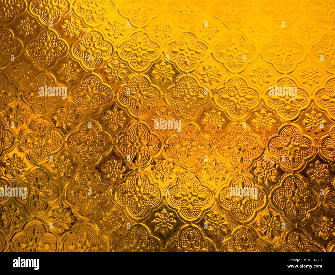 Intricate golden ornamental pattern with embossed floral and geometric motifs on a textured surface - Smartphone Captured Stock Image