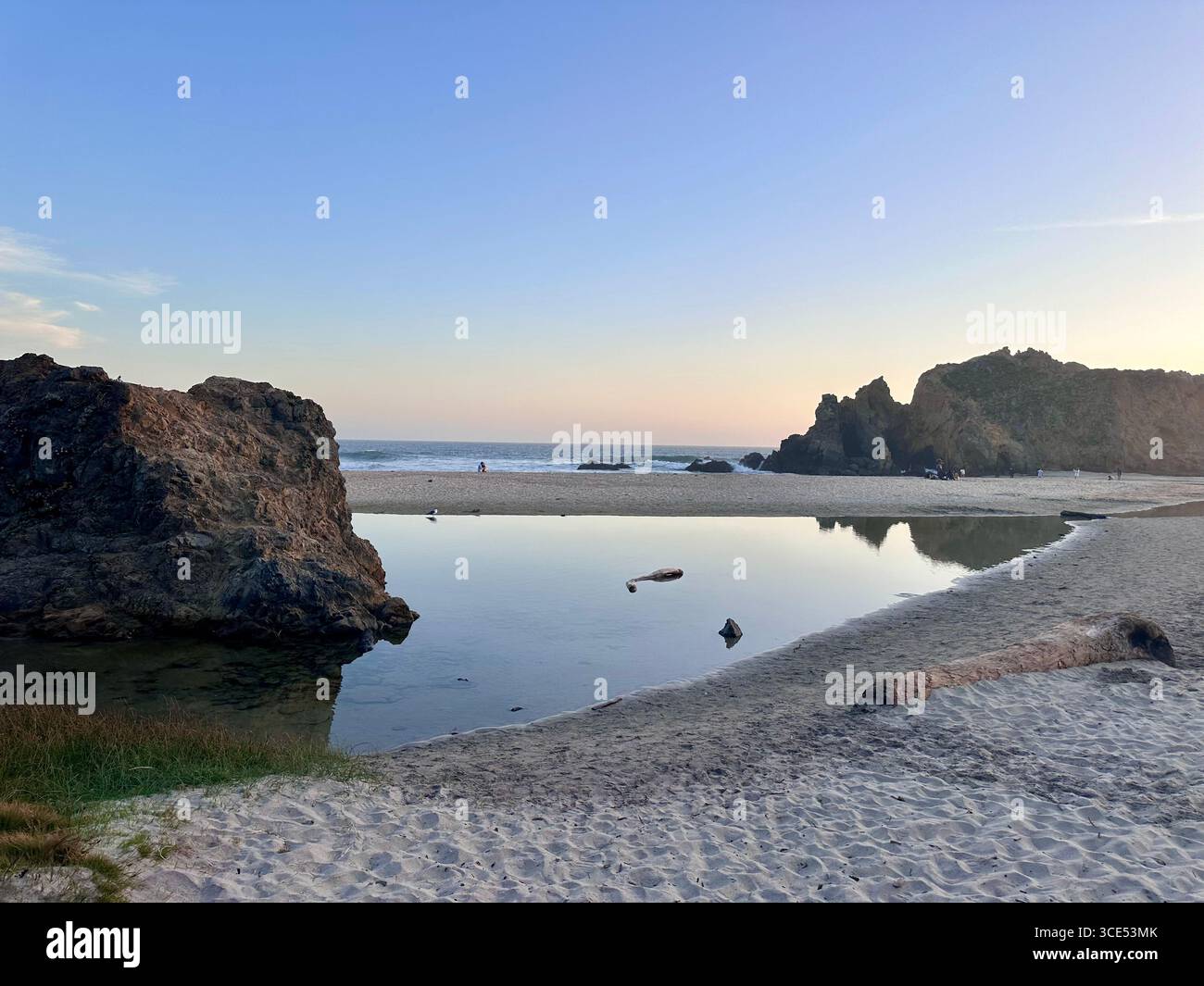 A tranquil scene at Pfeiffer Beach in Big Sur, California, showing a peaceful lagoon reflecting the rocky cliffs and pastel evening sky. - Smartphone Captured Stock Image