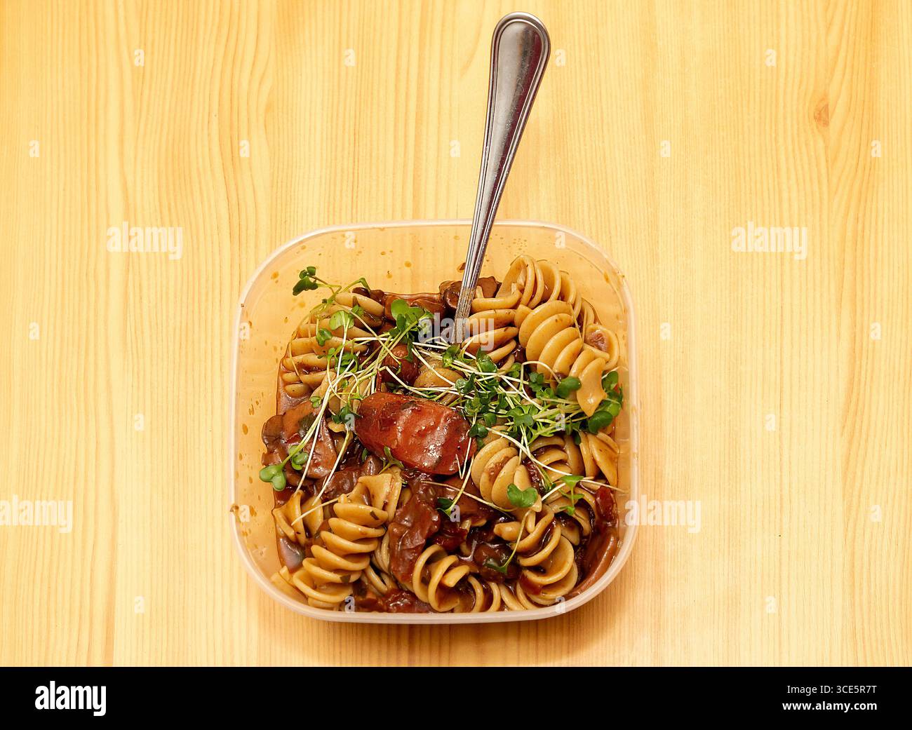 Fresh cooked pasta inside plastic bowl on wooden table Stock Photo