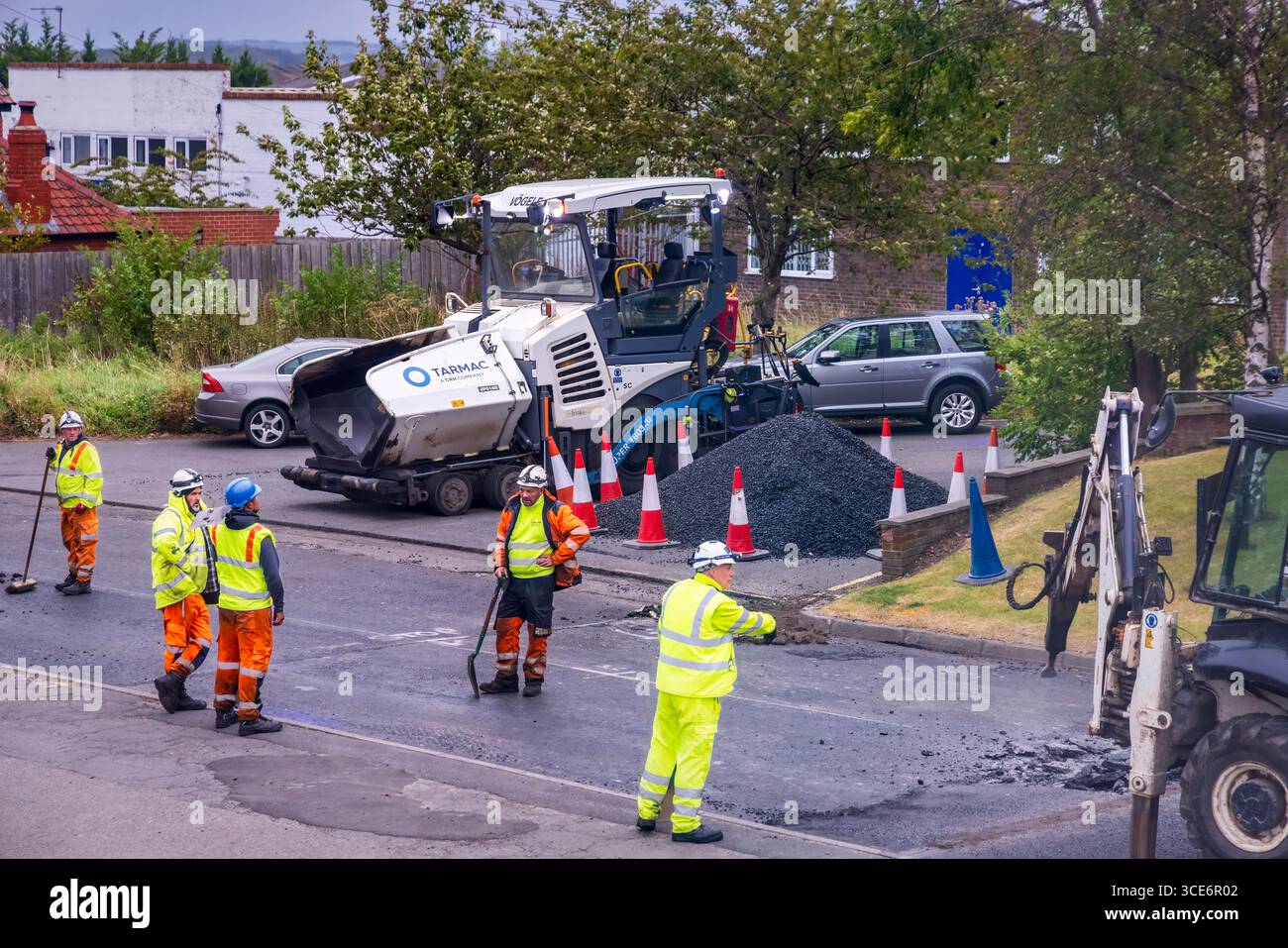 Road construction workers, machinery and equipment, resurfacing carriageway, Stokesley, North Yorkshire, England, UK Stock Photo