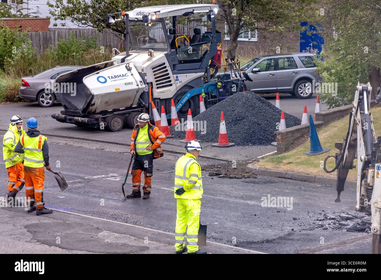 Road construction workers, machinery and equipment, resurfacing carriageway, Stokesley, North Yorkshire, England, UK Stock Photo