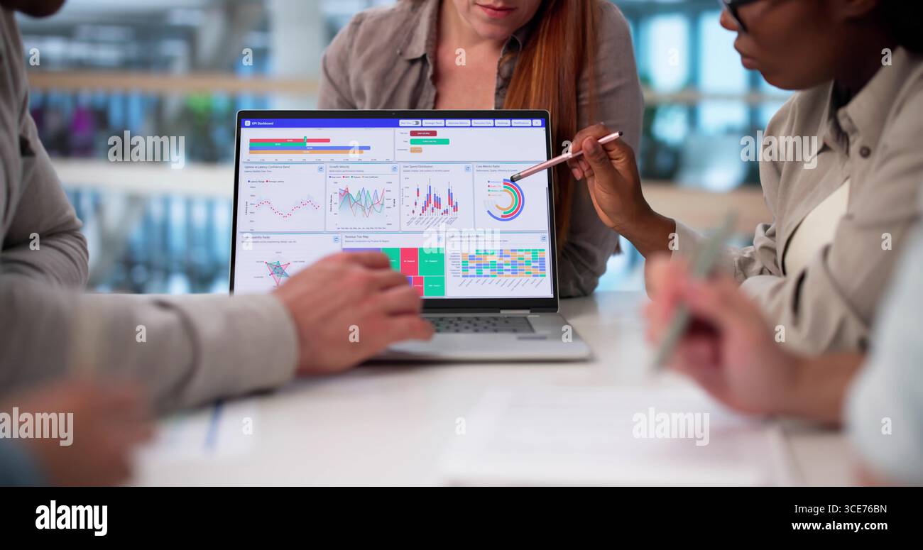 Diverse Team Of Analysts Collaborate On Predictive Business Analytics Dashboard. Stock Photo