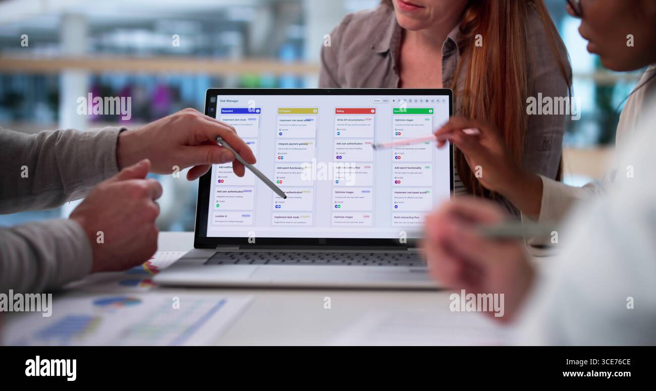 Diverse Group Of Young Professionals Collaborating On Software In Office. Stock Photo