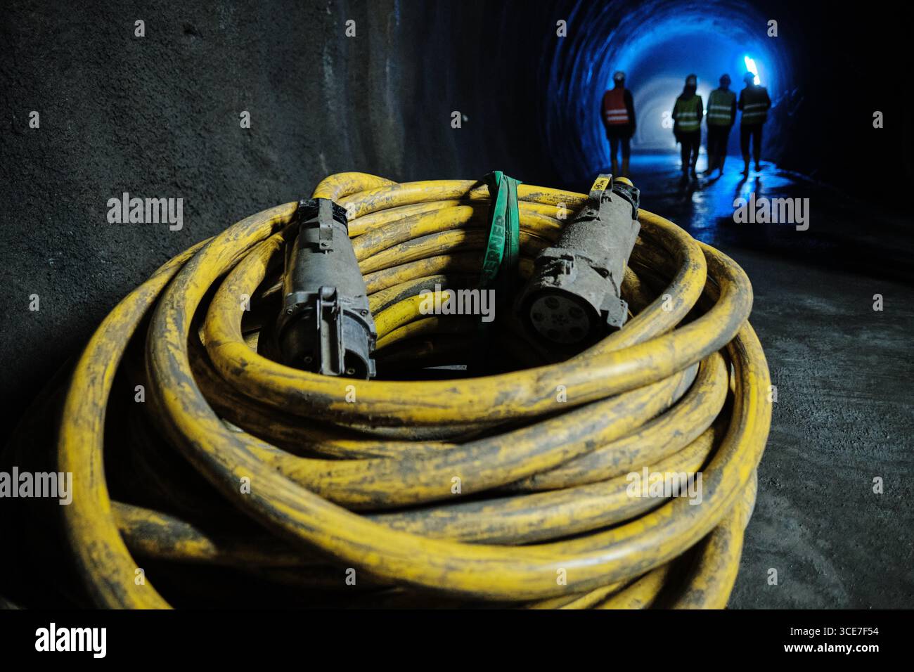 Schwere Stromkabel im Wasserstollen mit Arbeitern im Hintergrund Stock Photo