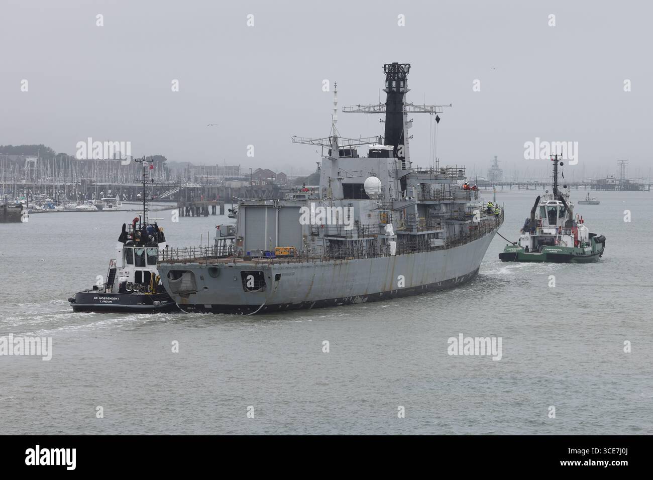 The Royal Navy frigate HMS NORTHUMBERLAND is towed towards a berth in the Naval Base at the end of its journey from Plymouth dockyard. Stock Photo