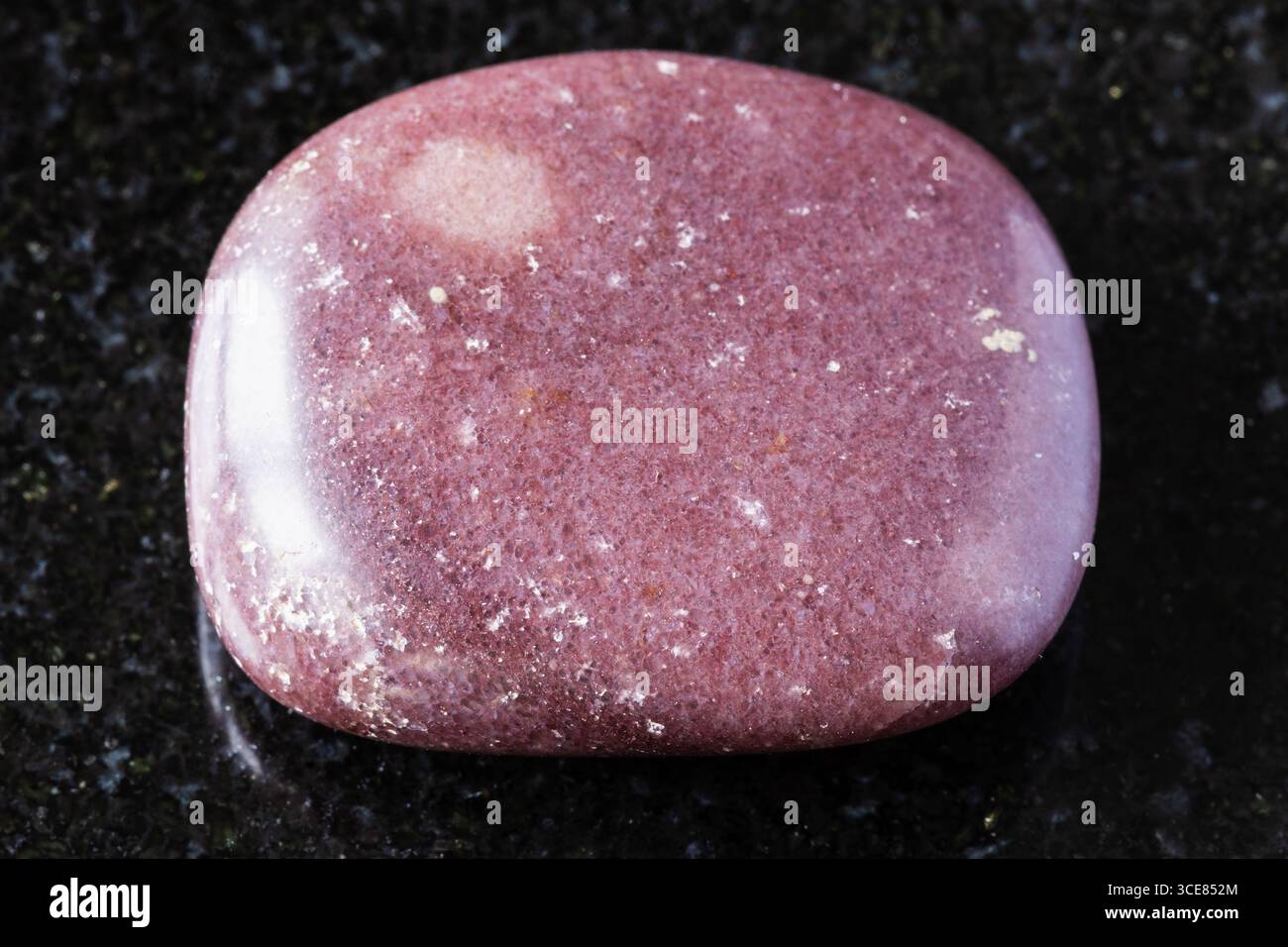 sample of polished red brown quartzite rock on black granite background close up from Karelia, Russia Stock Photo