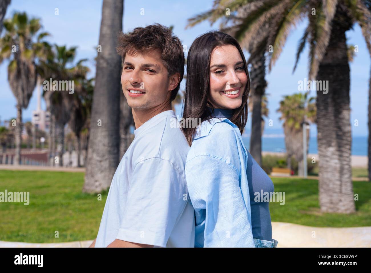 Smiling young couple standing back to back outdoors Stock Photo