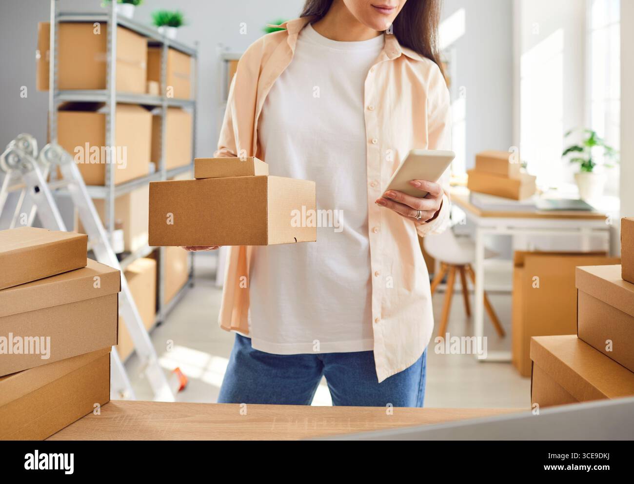 Internet store owner or inventory manager preparing parcels and using mobile phone Stock Photo