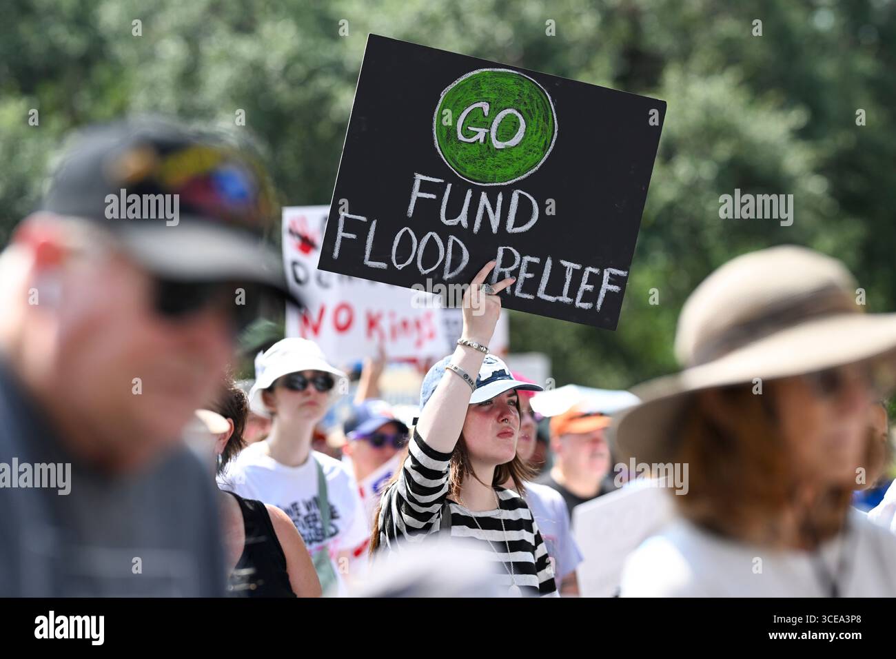 Austin, United States. 16th Aug, 2025. A woman holds a sign asking for flood relief after recent Texas storms during a 'Fight The Trump Takeover' progressive rally at the Texas Capitol in Austin on August 16, 2025. Hundreds of Democrats and progressive Texans decried Republican redistricting efforts and Gov. Greg Abbott's handling of flood relief. Credit: Bob Daemmrich/Alamy Live News Stock Photo