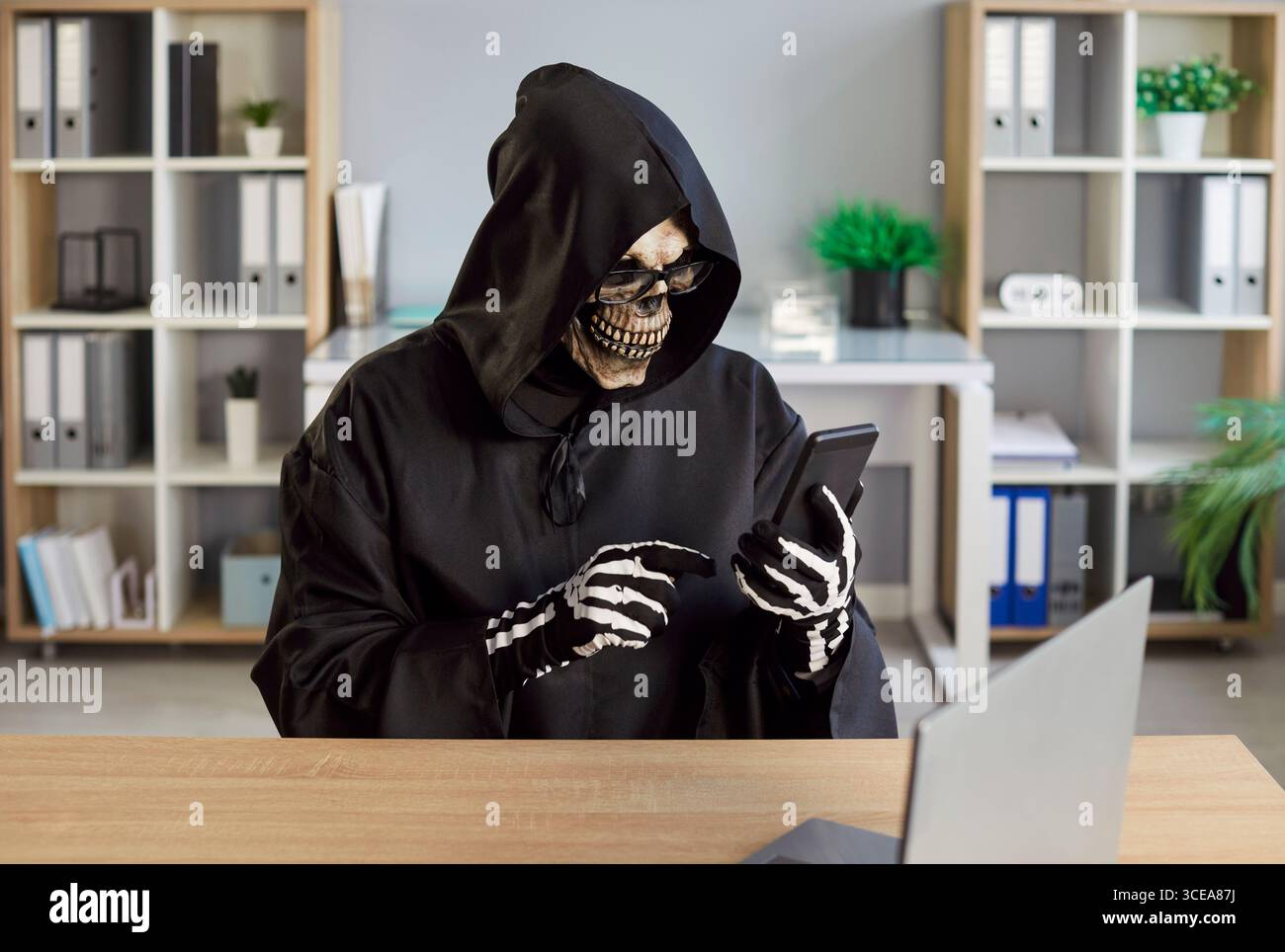 Smartphone thefts, robberies, scary dangerous hacker Halloween Grim Reaper horrific figure Stock Photo