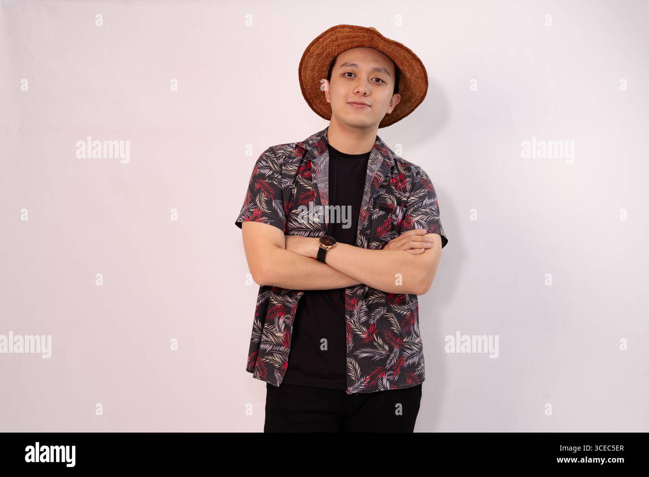 casual young man posing with crossed arms and wearing straw hat Stock Photo