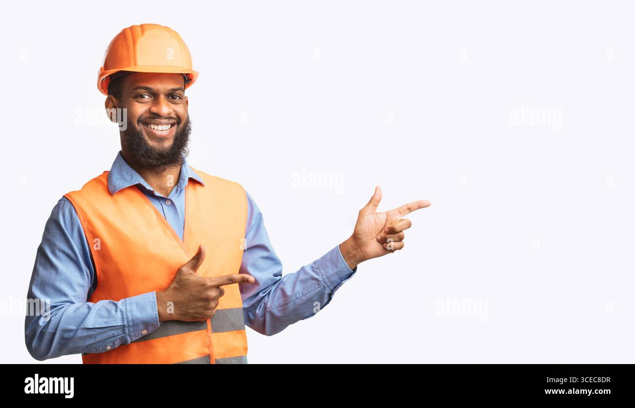 Builder Guy In Uniform Pointing Fingers Aside On White Background Stock Photo