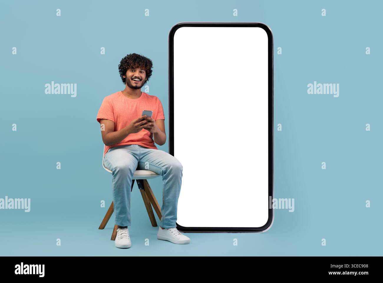 Cheerful curly eastern guy enjoying newest mobile app Stock Photo