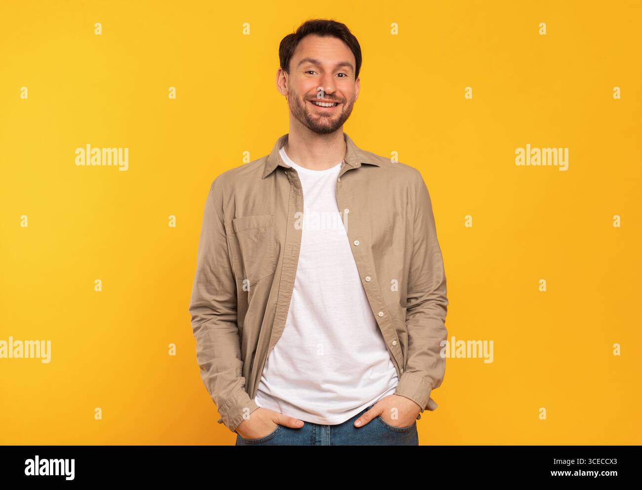 Smiling Man In Brown Shirt Standing Against Yellow Background Stock Photo