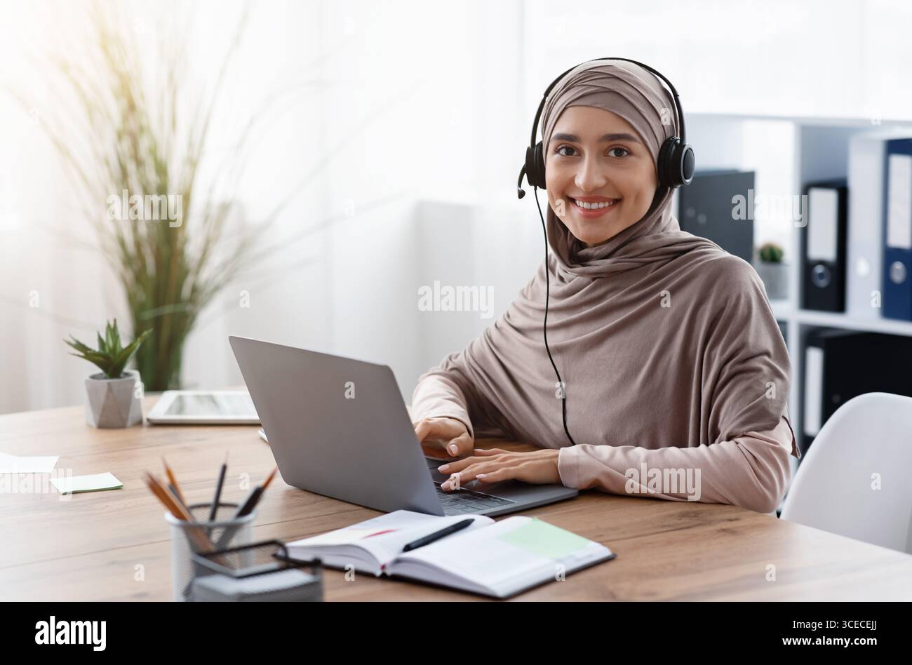 Arab female call center operator in hijab and headset at workplace ...