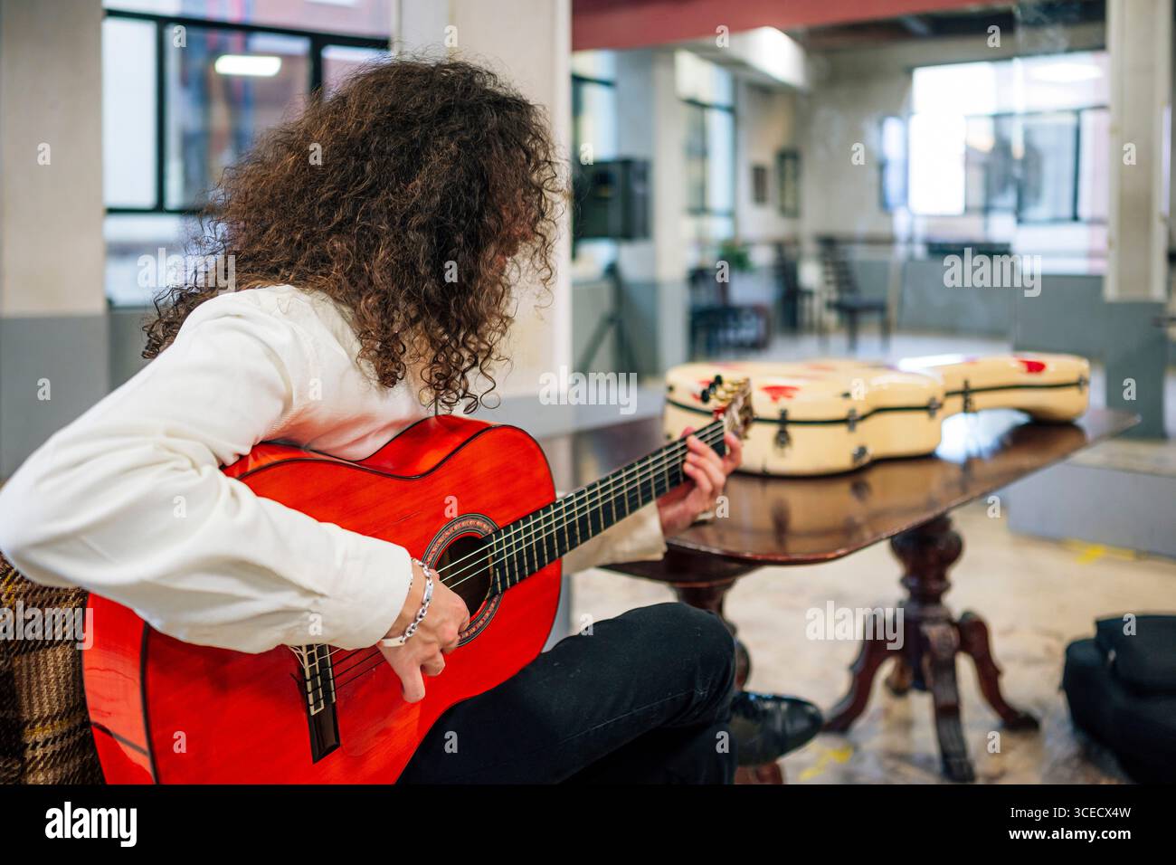 Latin man with long hair playing red bass guitar in studio Stock Photo
