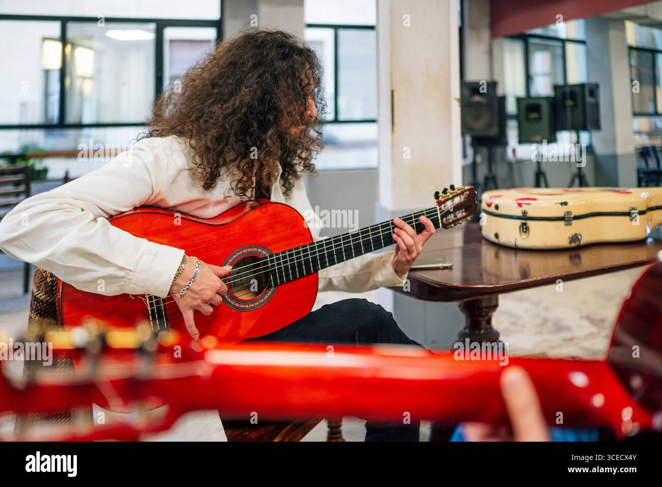 Latin man with long hair playing red bass guitar in studio Stock Photo