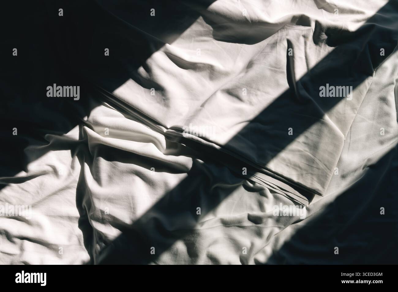 Shadow and light pattern on crumpled cotton bedsheet, top view Stock Photo