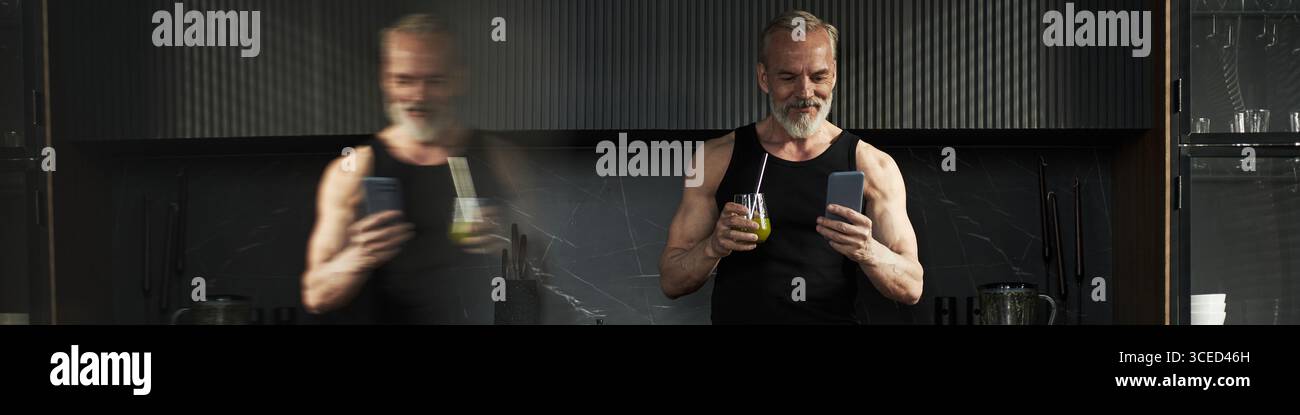 Middle Aged Caucasian Man Smiling While Using Smartphone and Drinking Juice Stock Photo