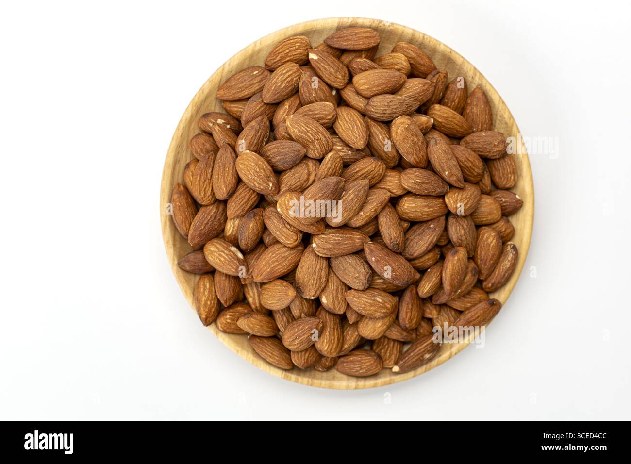 A top view wooden plate filled with roasted almond, healthy snack, brown nut, isolated on white background, natural food, crunchy texture, delicious Stock Photo