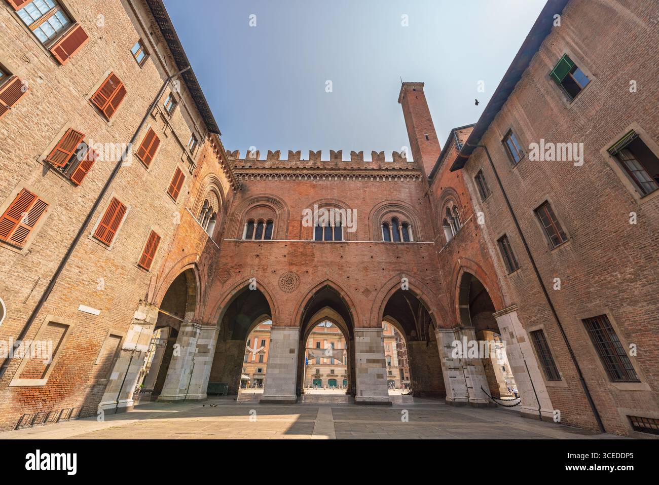 Wide-angle view of the historic Palazzo Gotico courtyard in Piacenza, Italy, showing Gothic arches, red brick walls, and medieval details Stock Photo