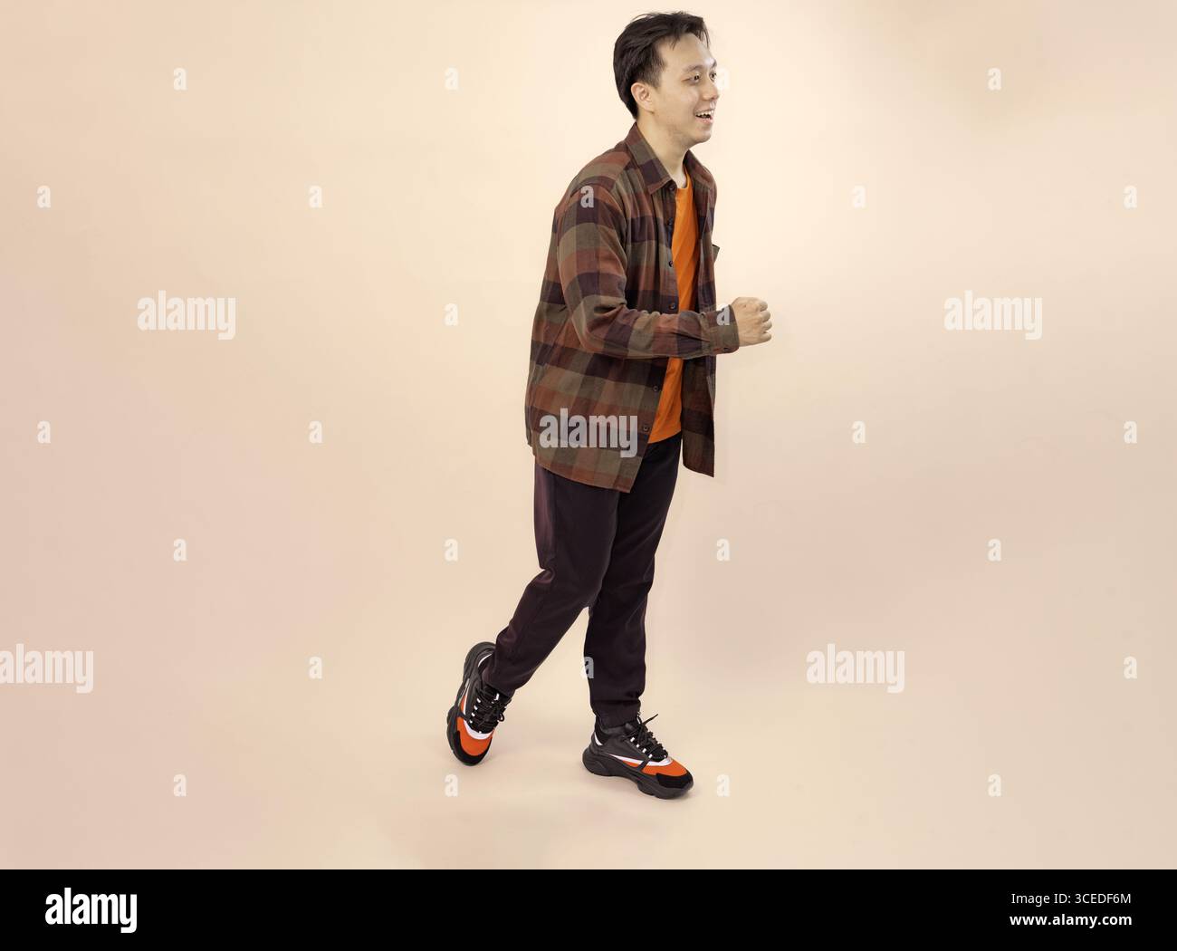 casual young man walking in style on beige background Stock Photo