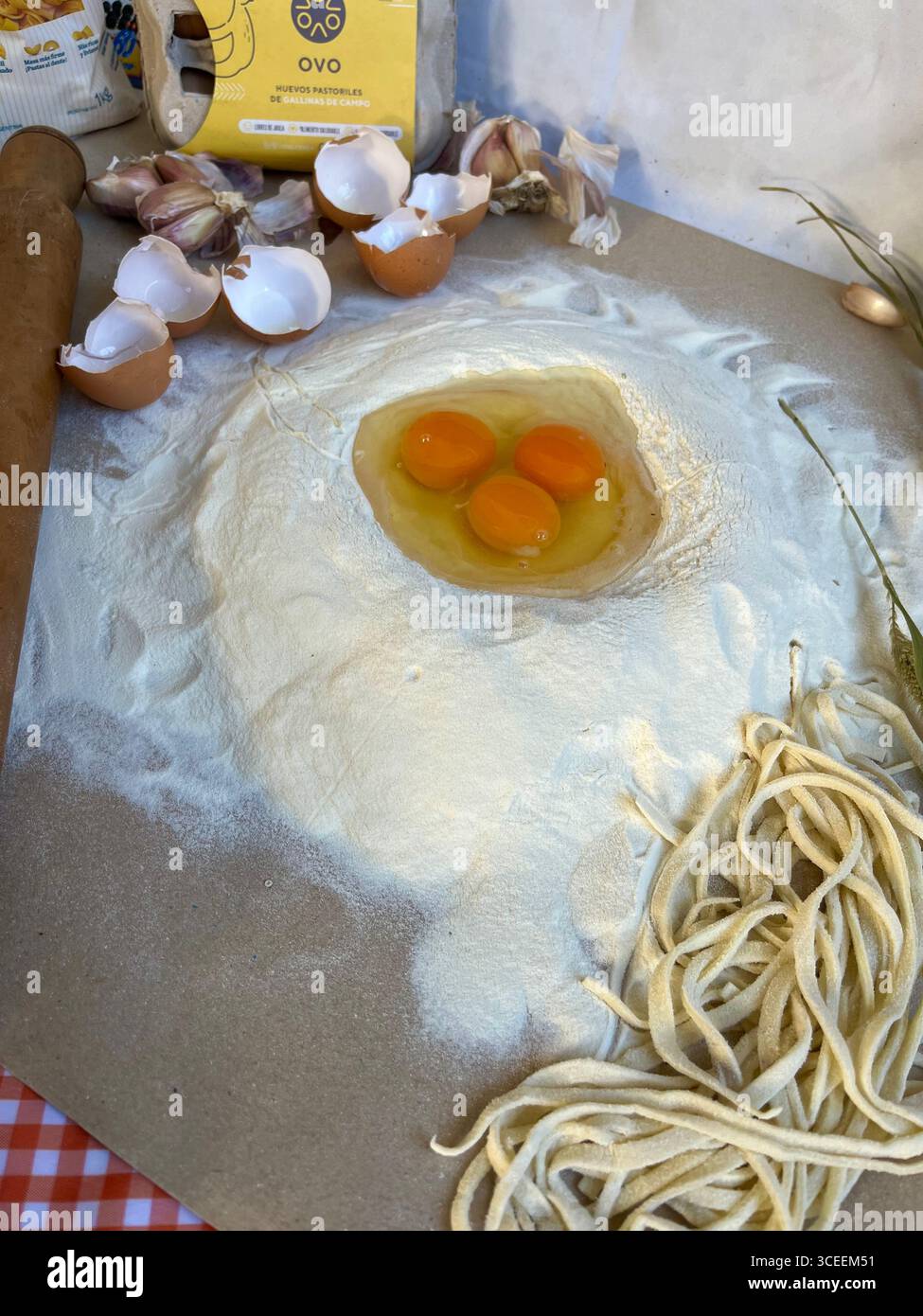 Freshly made pasta nests with egg yolks resting on a floured wooden board, ready for cooking. - Smartphone Captured Stock Image