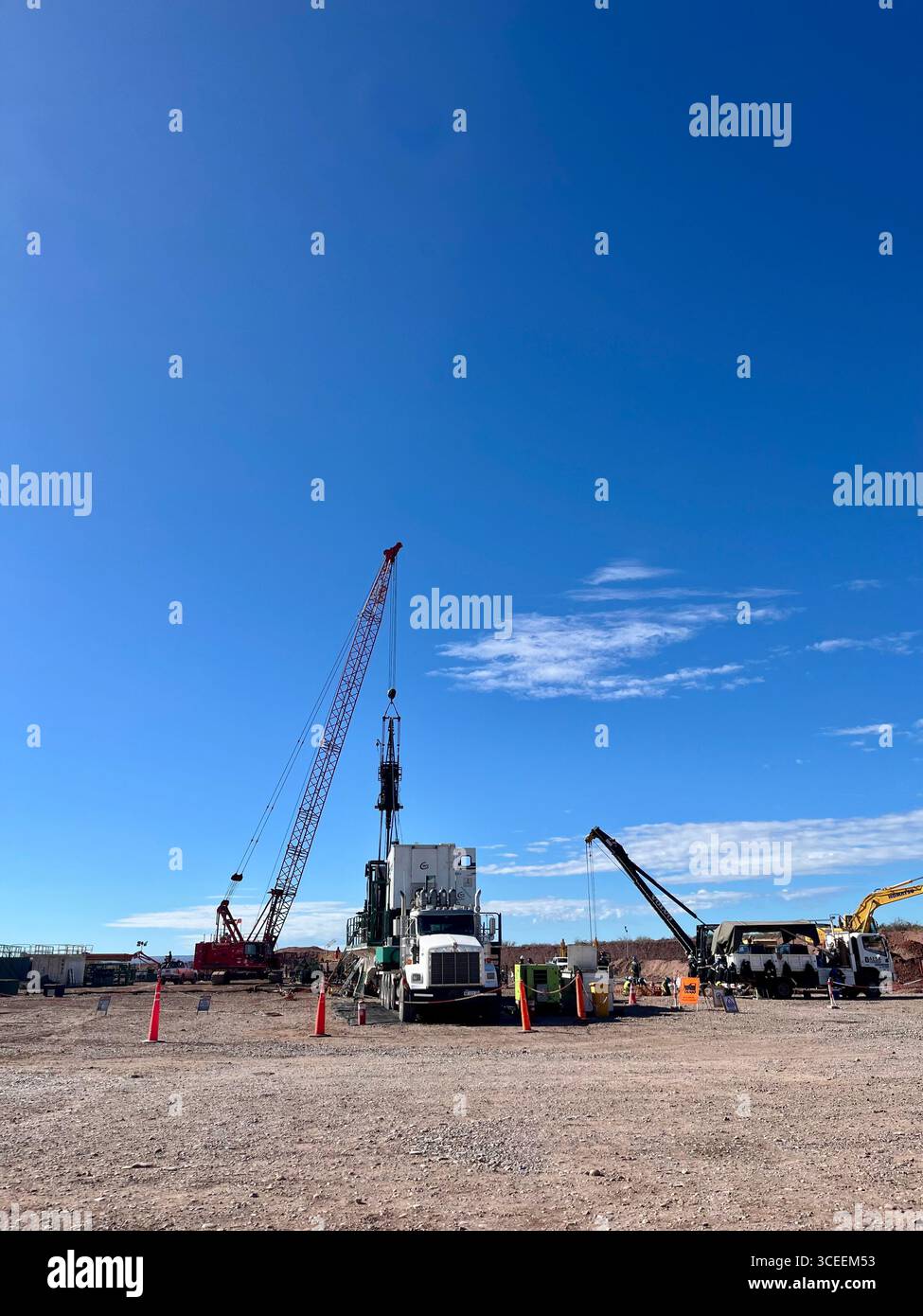 Construction site with cranes, trucks, and heavy equipment under a clear blue sky on a sunny day. - Smartphone Captured Stock Image