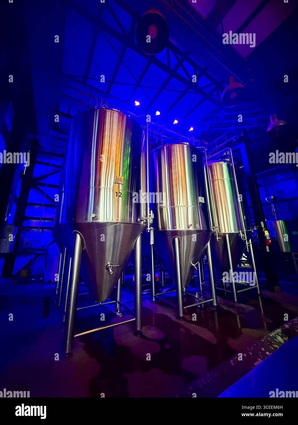 A contemporary installation of metallic tubes illuminated by vibrant blue and purple stage lights on a platform in a dark venue. - Smartphone Captured Stock Image