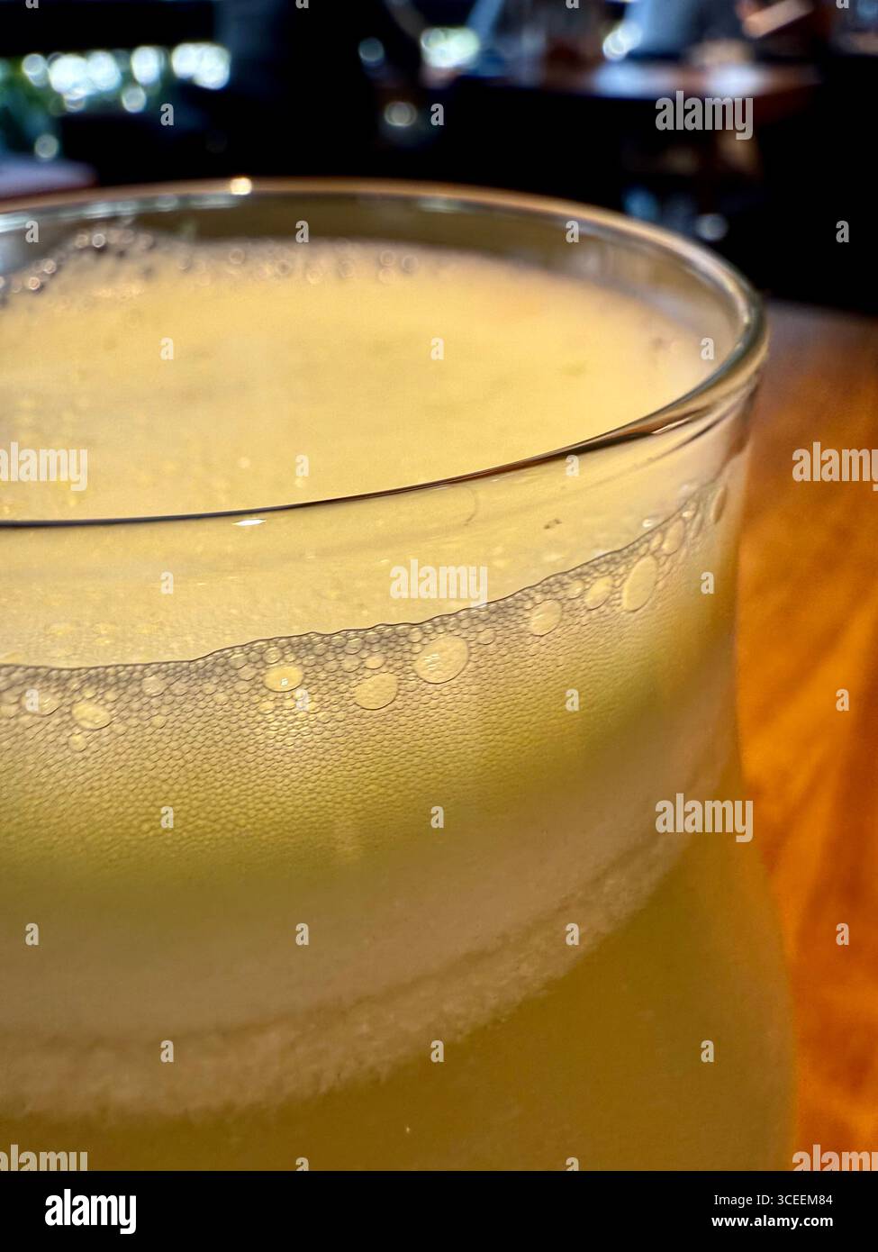A frothy yellow beverage served in a glass on a table, refreshing and inviting at a restaurant. - Smartphone Captured Stock Image