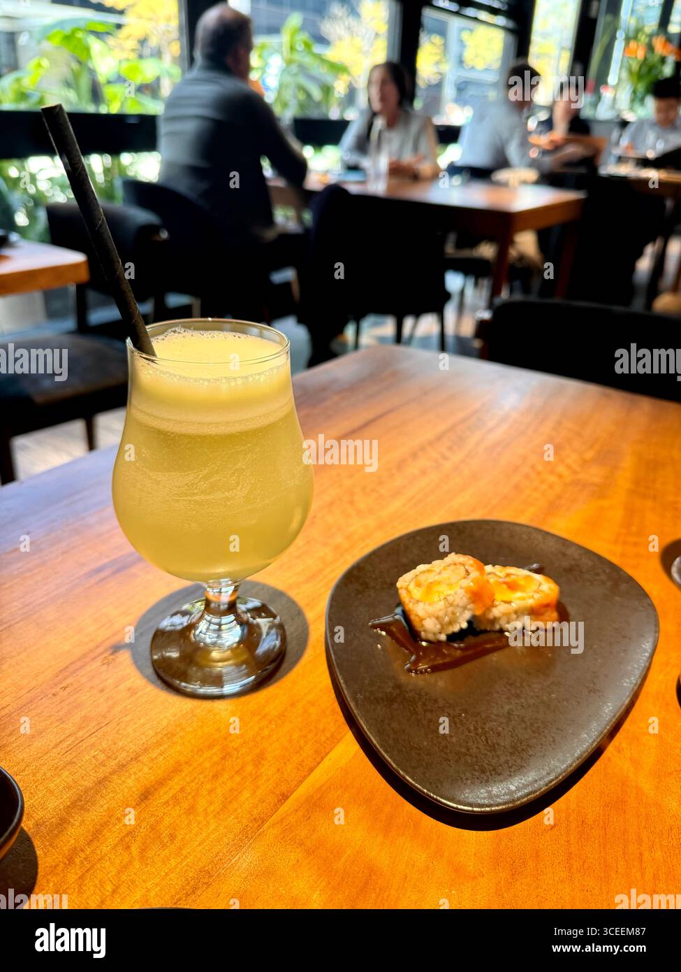 A refreshing tropical cocktail served with a lemon garnish and a small snack on a table. - Smartphone Captured Stock Image