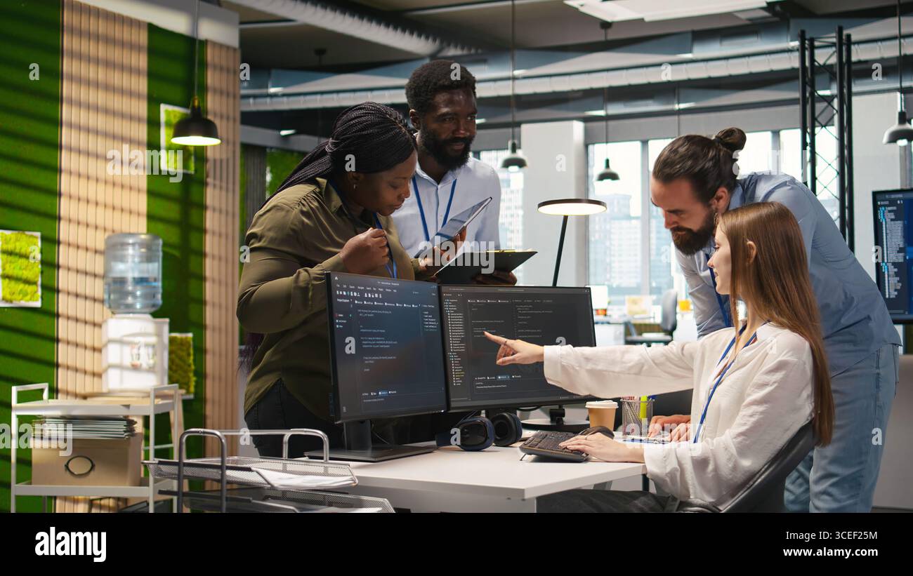 Welcoming team assisting intern developing artificial intelligence models for business analytics. Friendly coworkers helping junior dev running simulations for AI driven forecasting, camera A Stock Photo