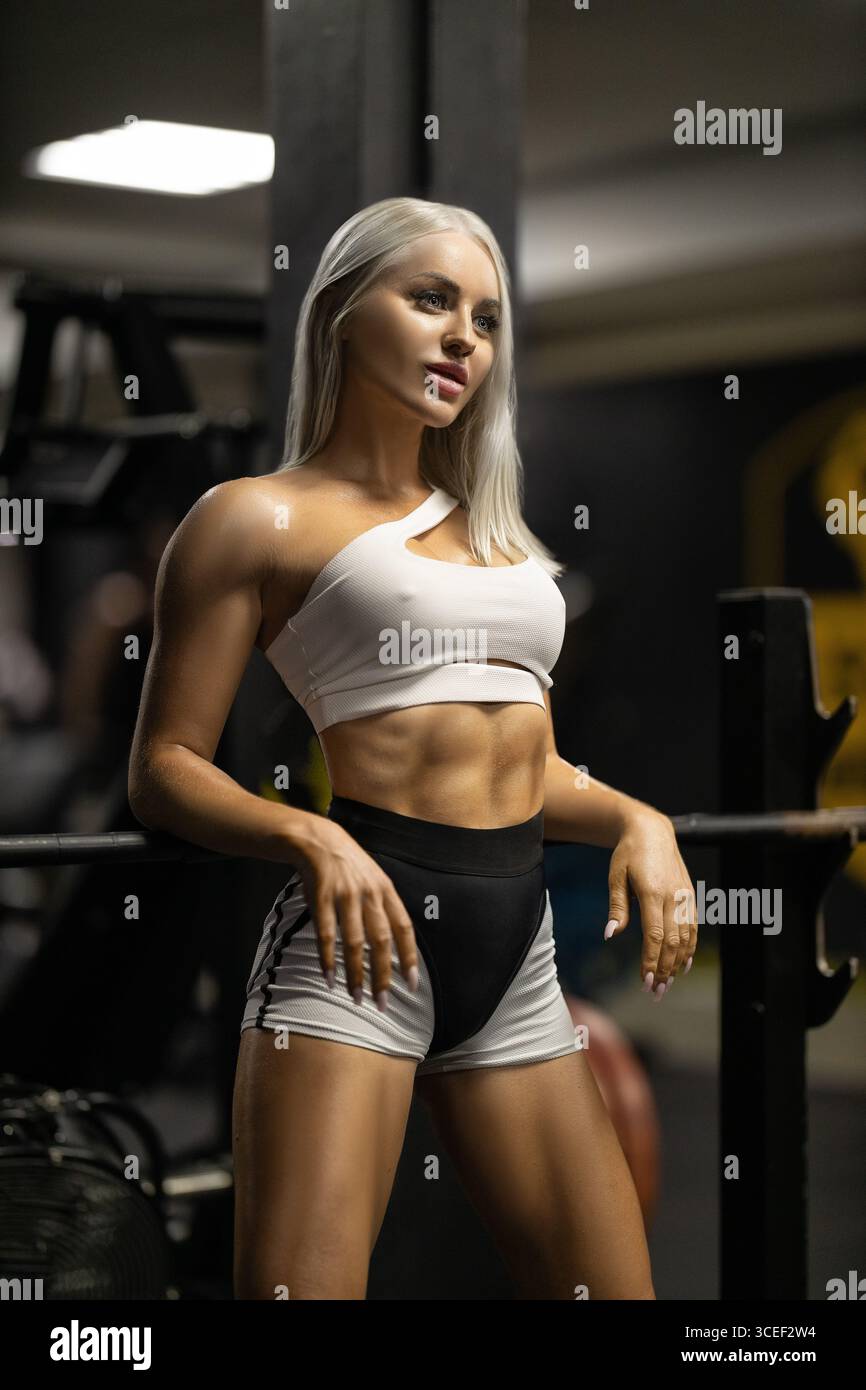 fit woman showcases toned abs and muscular physique while leaning ...