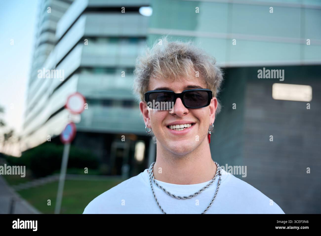 Blond gen z influencer smiling wearing sunglasses and silver chains Stock Photo