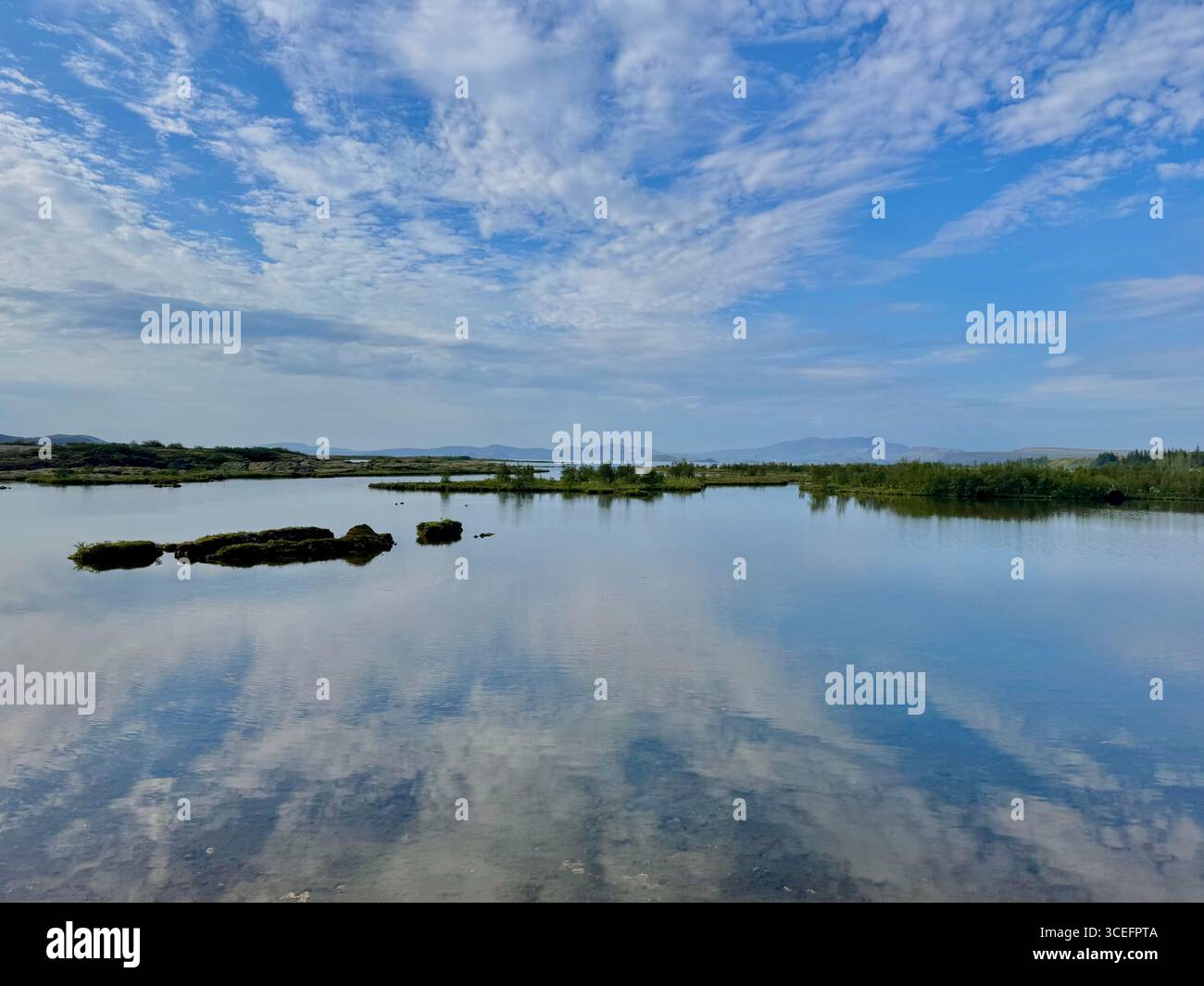 Thin summer clouds reflect on the ultra clear Silfra fissure water at Thingvellir National Park in summer. - Smartphone Captured Stock Image