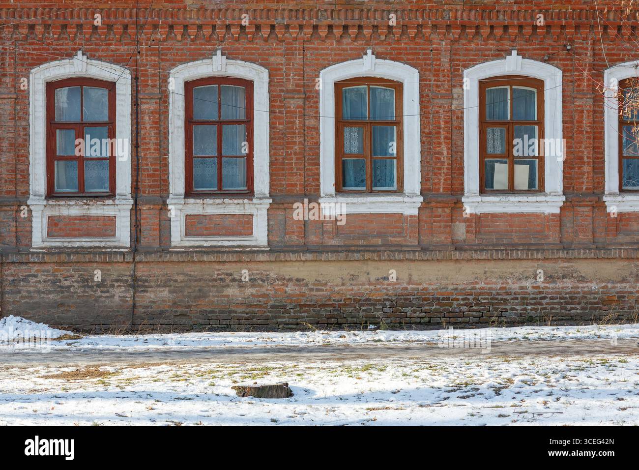 Facade of an old red brick building with white arched window frames and ...