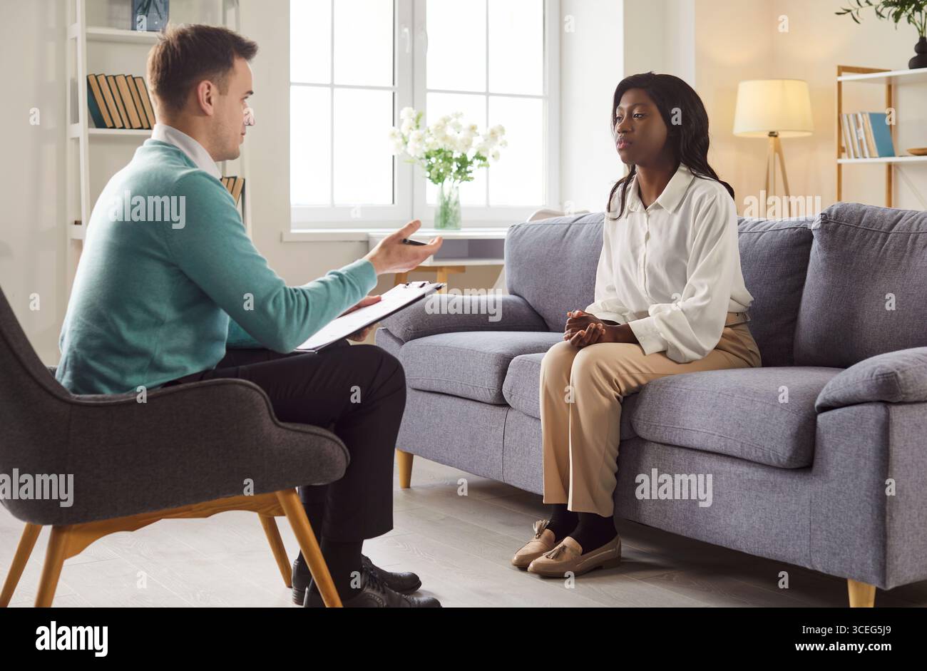 Female client sitting on couch, talking to professional male ...