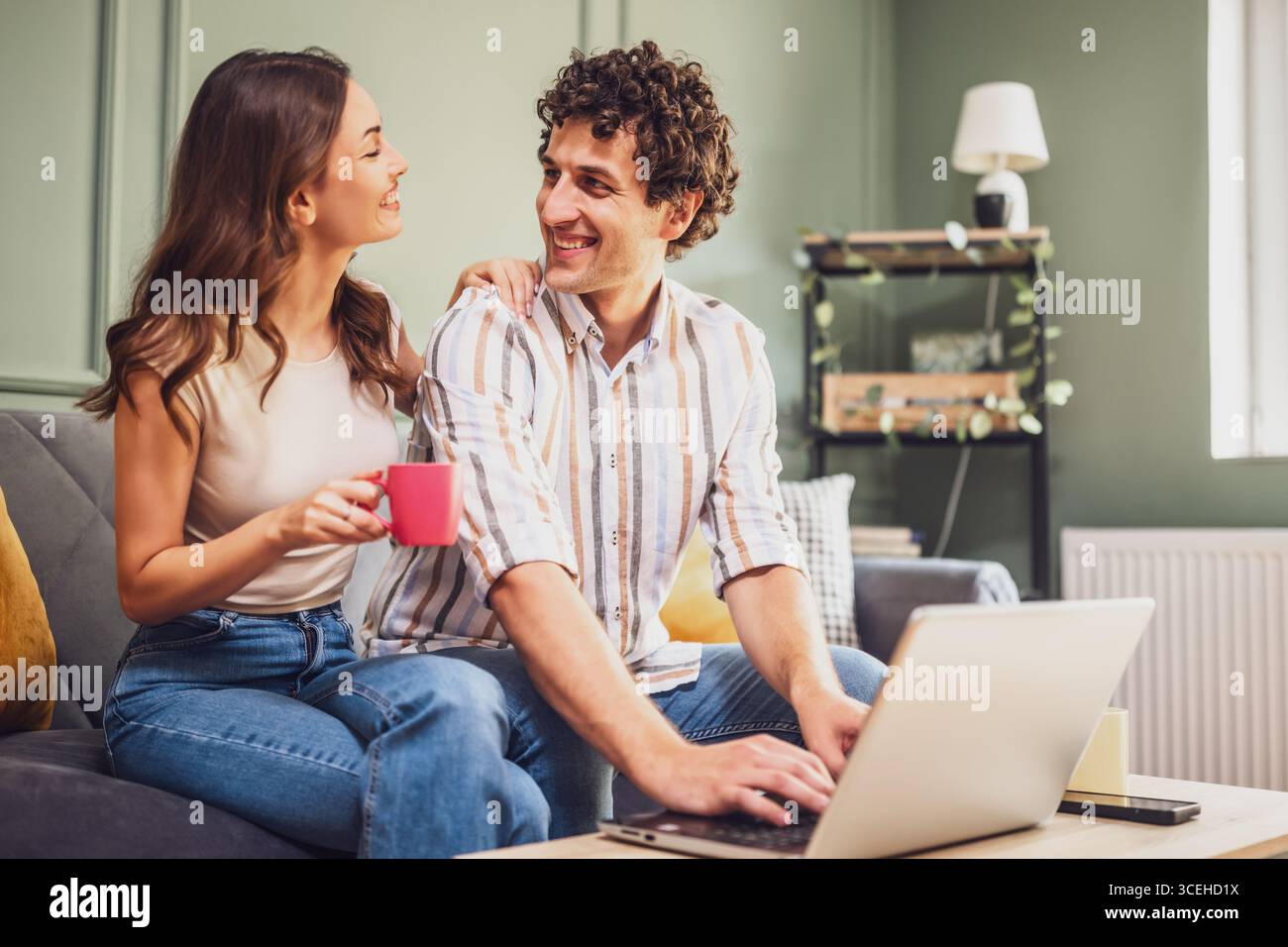 Couple discussing home finance on laptop and calculating family budget in living room. Stock Photo