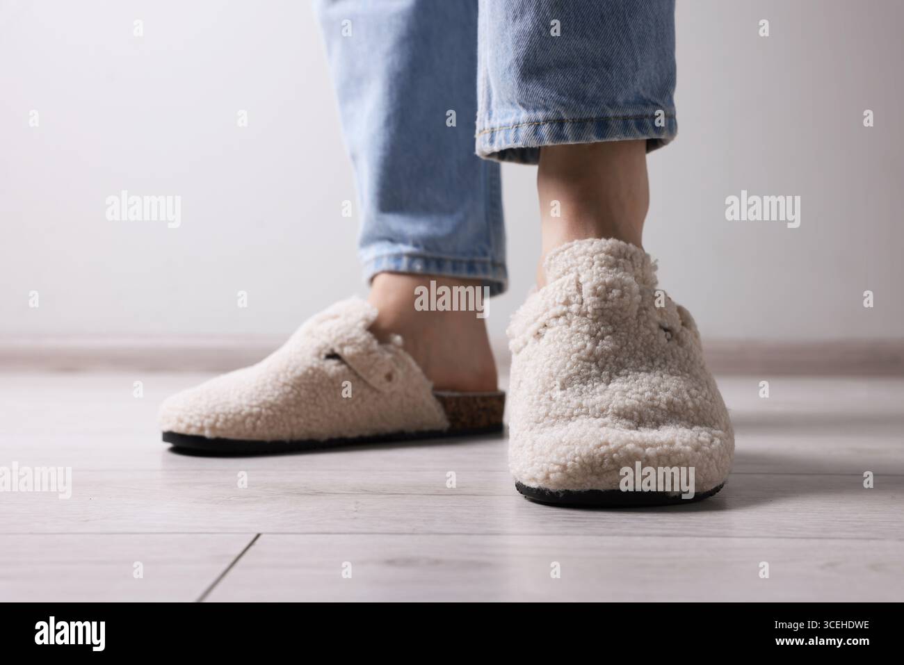 Woman In Soft White Slippers On Light Wooden Floor Closeup Stock Photo woman-in-soft-white-slippers-on-light-wooden-floor-closeup-stock-photo