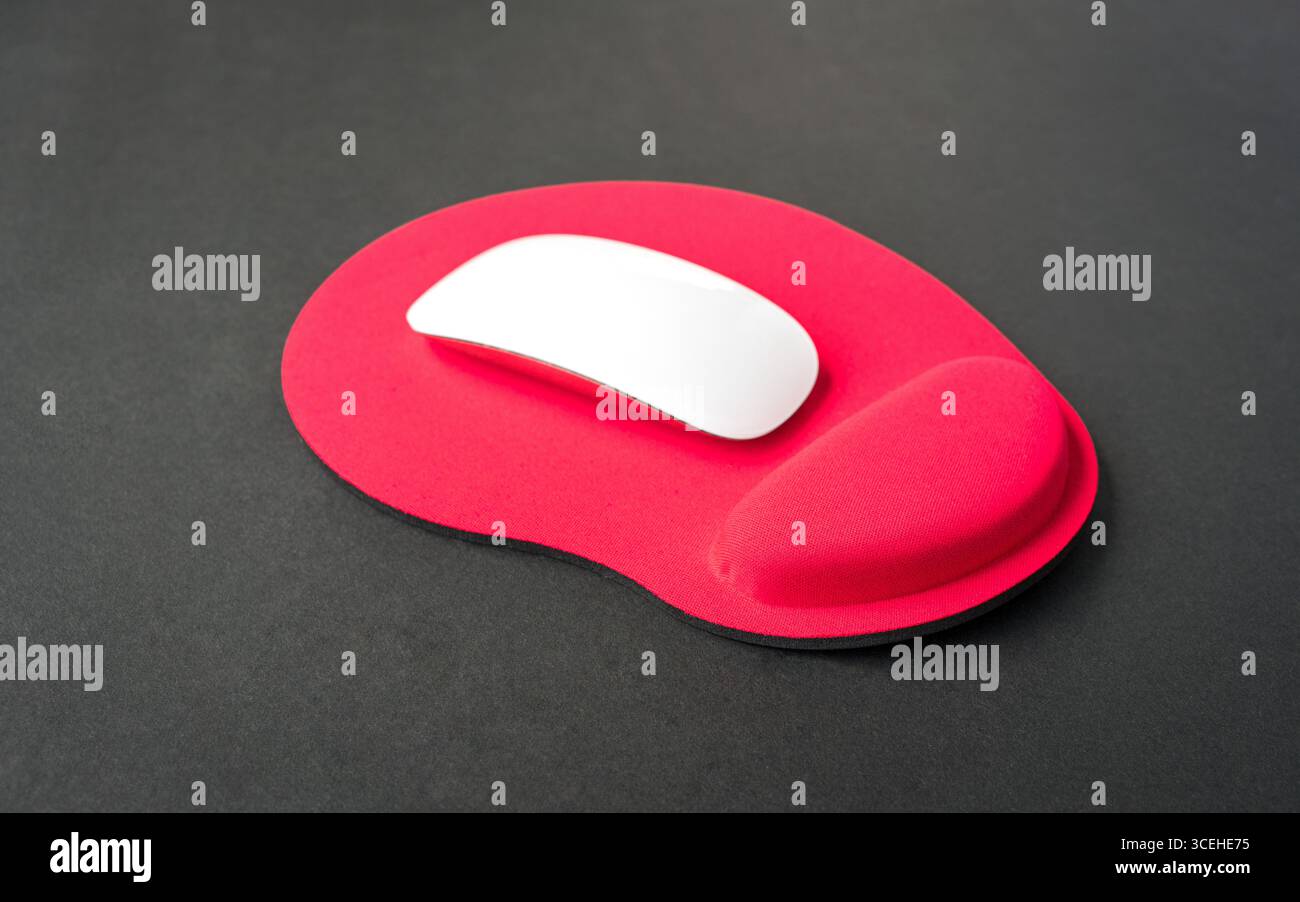 Red color wrist rest mousepad with computer mouse on top. Stock Photo