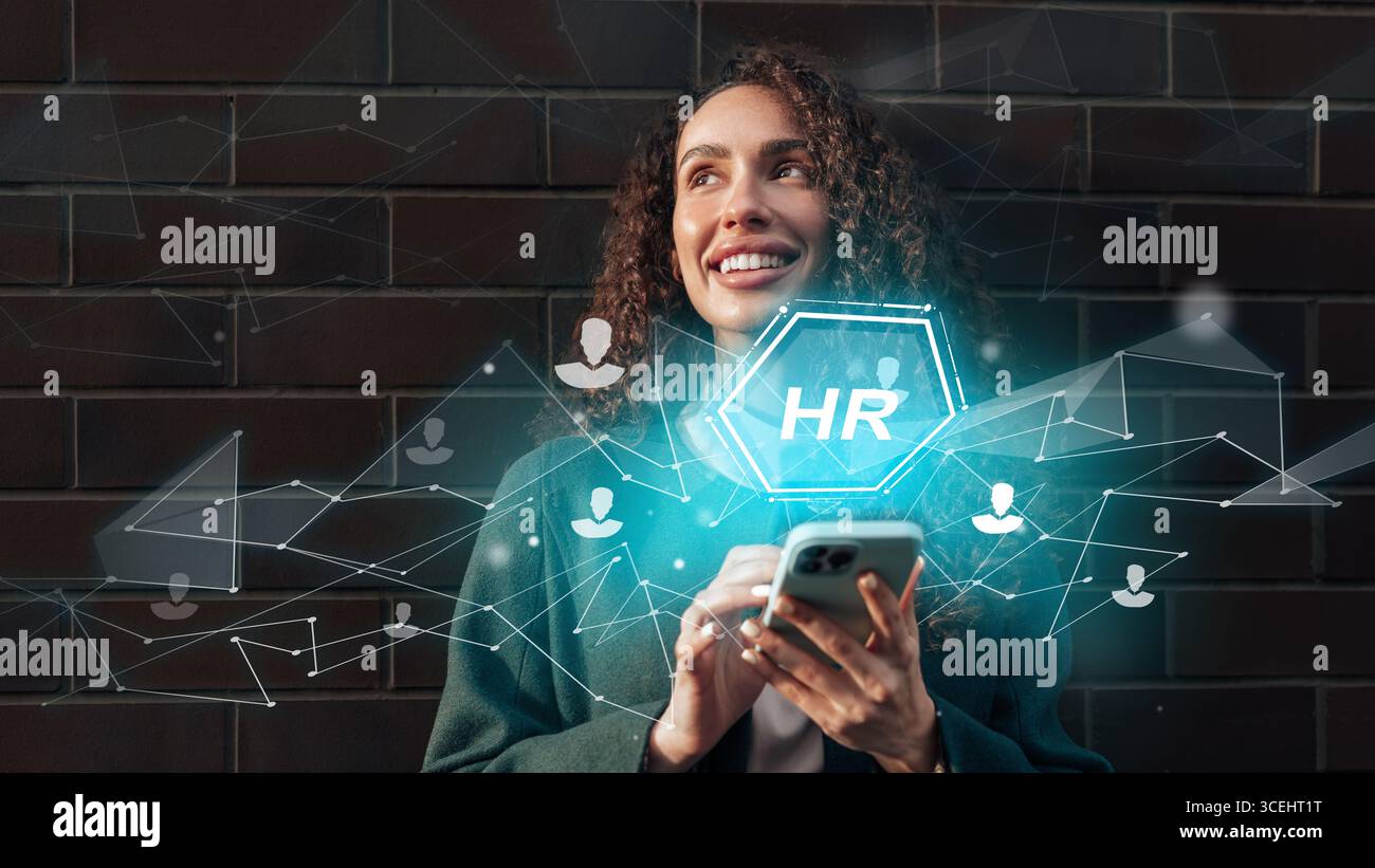 HR professional engaging with technology while smiling outdoors during daytime Stock Photo