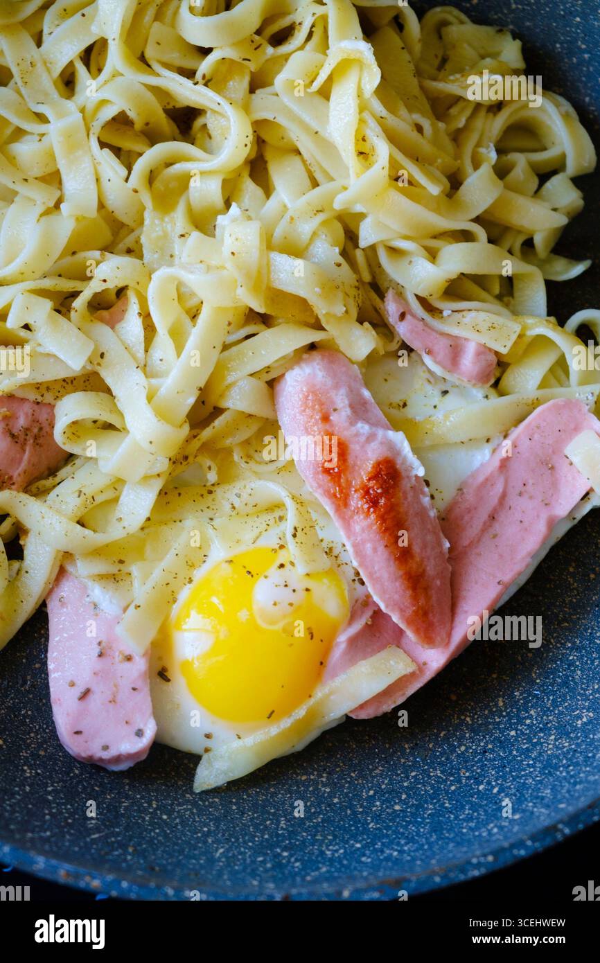 Picture of Pasta seasoned with aromatic herbs and spices cooks in a pan alongside ...