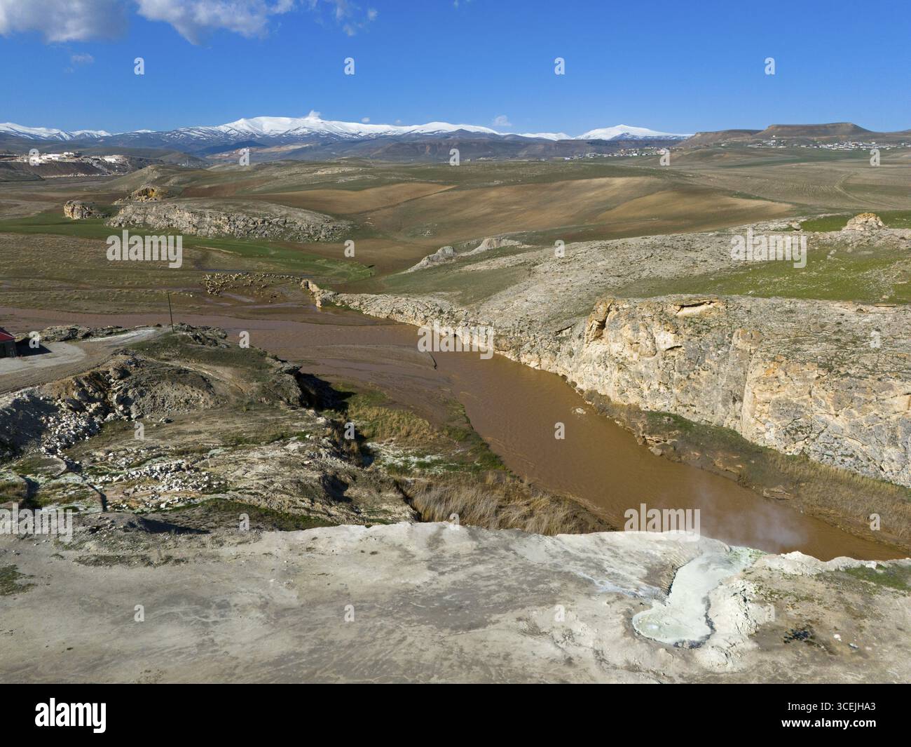Brown river flows through rugged rocks in a vast landscape under a clear blue sky, aerial view, Diyadin, Murat River, thermal spring, Agri Province, A Stock Photo