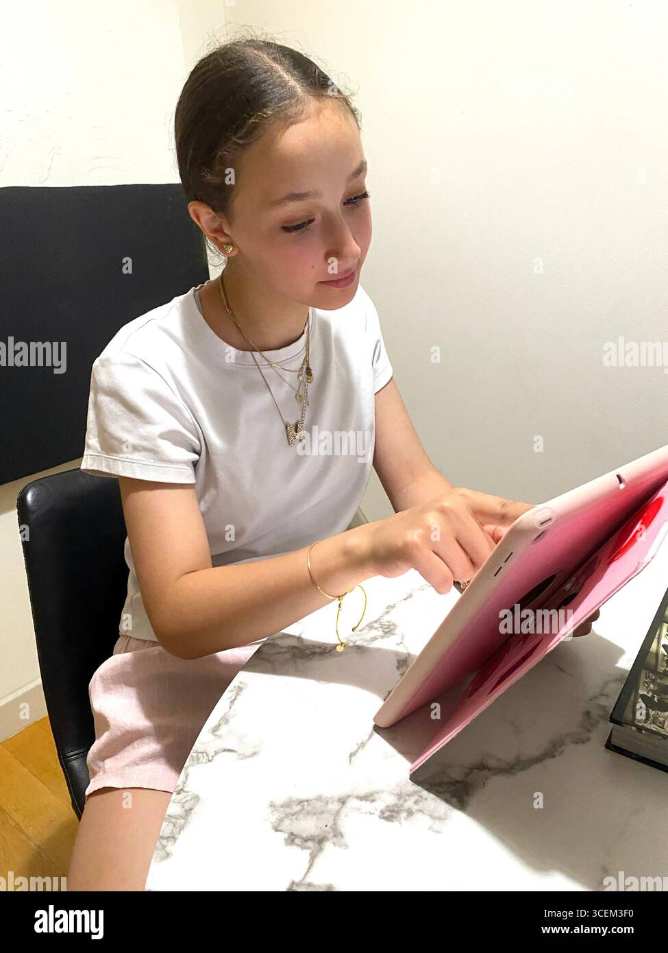 Pre-teen girl using her iPad at home. Model Released. - Smartphone Captured Stock Image